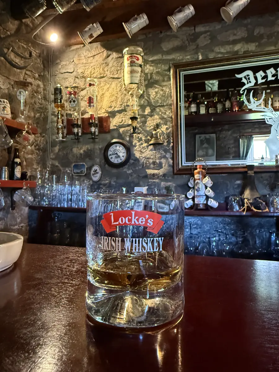 A glass of Locke's Irish whiskey on the bar, a carved Deerpark mirror behind
